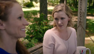 Two women talk on a porch swing.