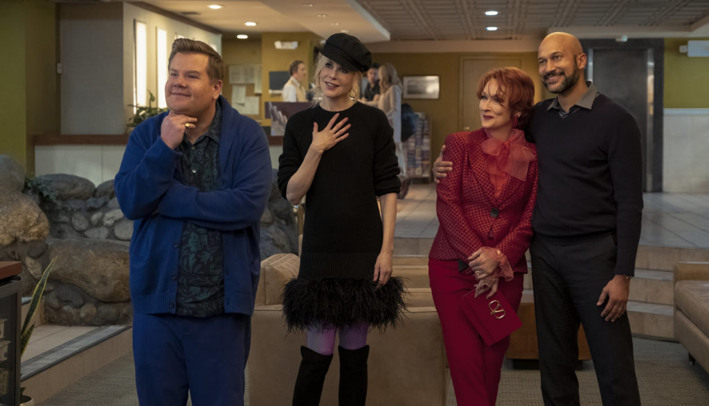 Four adults look excited in a hotel lobby.