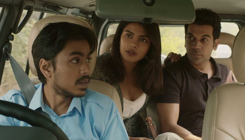 A driver in a car talks to two people in the back seat.